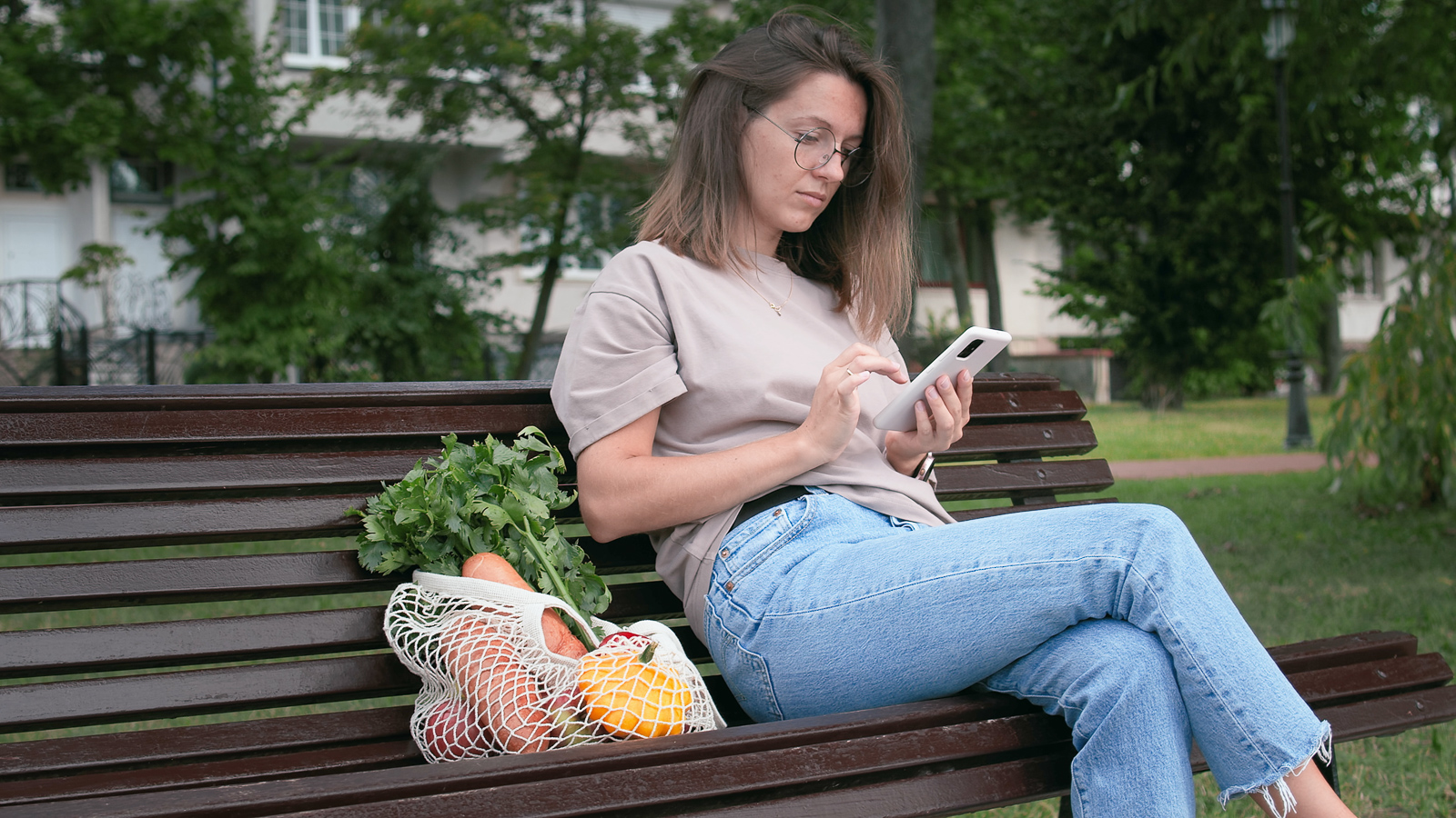 Woman on bench next to bag of fresh produce