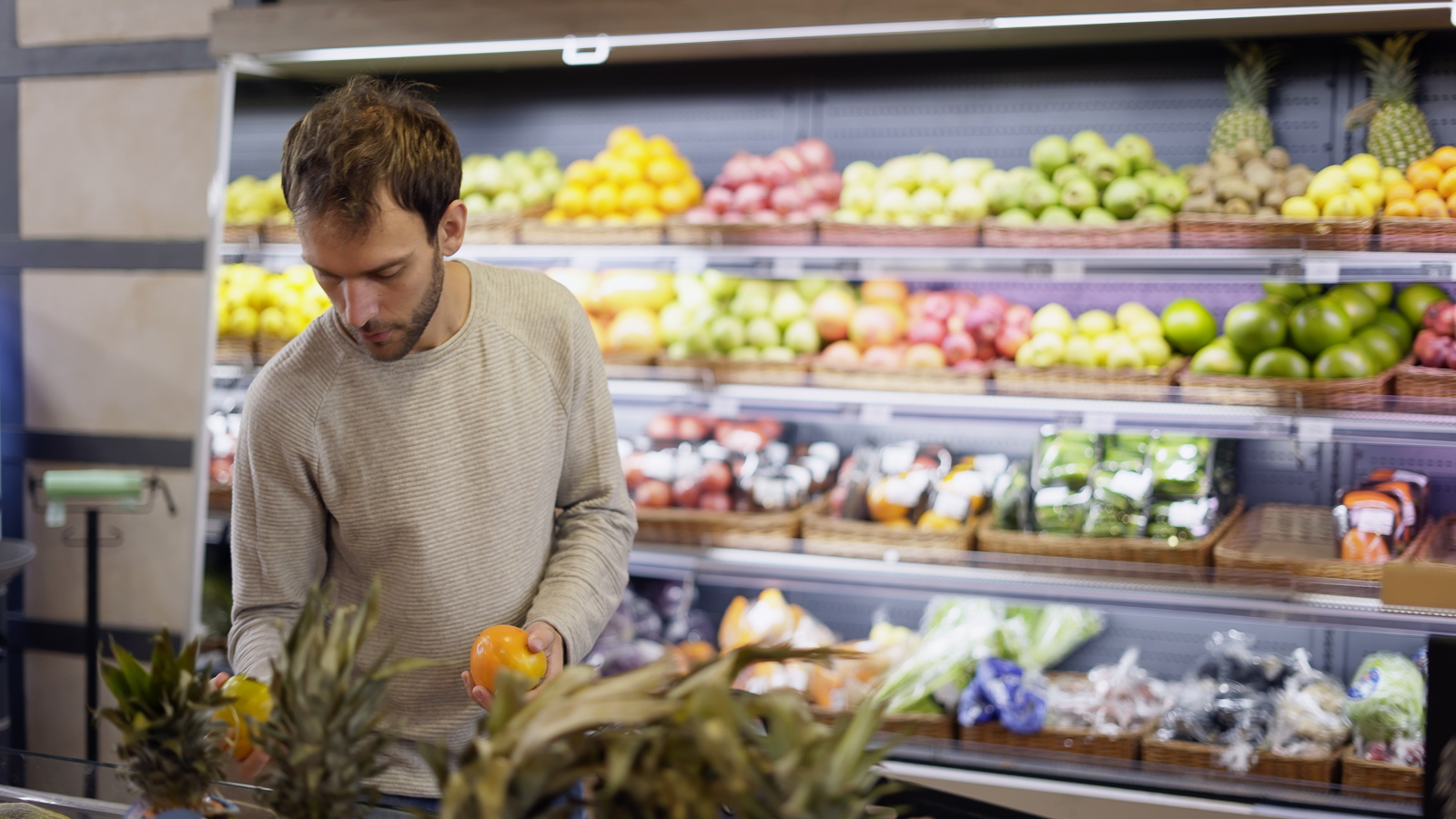 Man comparing apples in a grocery store